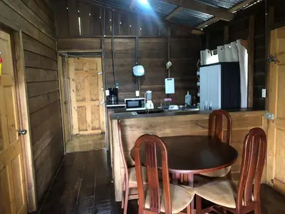 a kitchen with a table and chairs and a refrigerator at Cabaña El Bosque in Turrialba