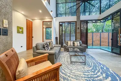 a living room with two couches and a glass table at Casa de Agua, A Jungle Retreat in Manuel Antonio in Manuel Antonio