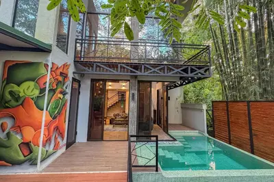 a house with a swimming pool and a walk in shower at Casa de Agua, A Jungle Retreat in Manuel Antonio in Manuel Antonio