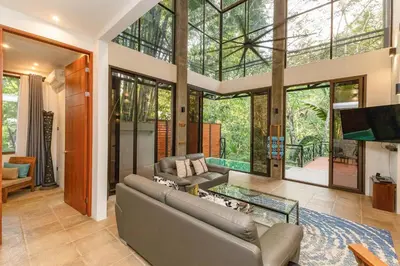 a living room with a couch and a glass table at Casa de Agua, A Jungle Retreat in Manuel Antonio in Manuel Antonio