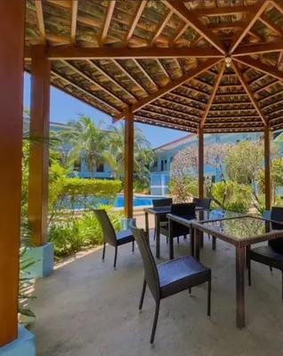 a patio with tables and chairs under a wooden pergola at Marina Loft in Coco
