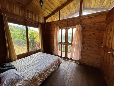 a bedroom with a bed in a wooden room with windows at Cabañas la esperancita in Guatuso