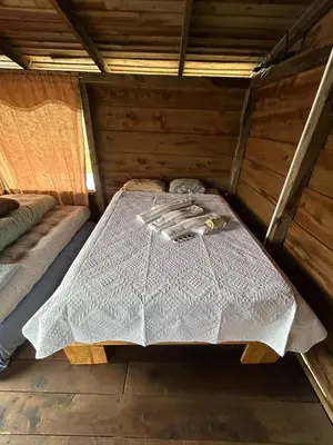 a bed in the inside of a wooden house at Cabañas la esperancita in Guatuso