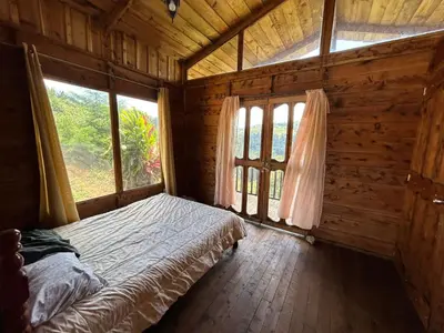 a bedroom with a bed in a wooden room with windows at Cabañas la esperancita in Guatuso