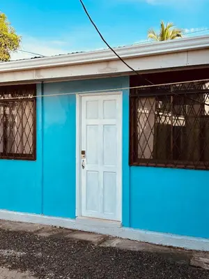 a blue and white building with a white door at Mini apartment in downtown Limón with AC in Puerto Limón