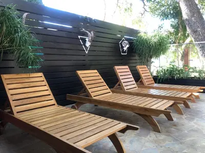 three wooden chairs sitting on a patio at Casa Aura: Beachfront Premium Hostel in Tamarindo