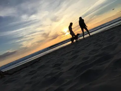 two people walking on the beach at sunset at Casa Aura: Beachfront Premium Hostel in Tamarindo