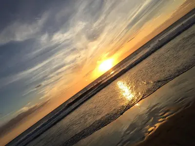 a sunset over the water on the beach at Casa Aura: Beachfront Premium Hostel in Tamarindo