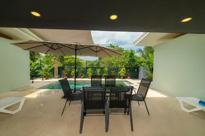 a table with chairs and an umbrella on a patio at Casa Tatala - 2bdr home with pool near Santa Teresa beach in Boca de Ario