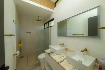a bathroom with a sink and a mirror and a toilet at Casa Tatala - 2bdr home with pool near Santa Teresa beach in Boca de Ario