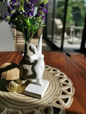 a white figurine on a table next to a vase with flowers at Our Paradise - Jaco Apartment in Jacó