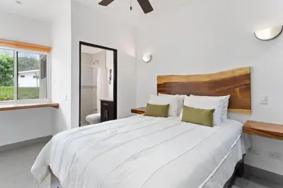 a white bedroom with a large bed and a bathroom at Cozy 3BR Townhouse Near Tamarindo-2 Pool&More in Santa Cruz