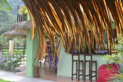 a group of stools under a thatched roof at Mavi Surf Hotel Dominical in Dominical
