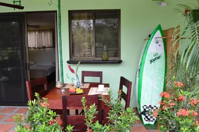 a room with a table and a surfboard on the wall at Mavi Surf Hotel Dominical in Dominical