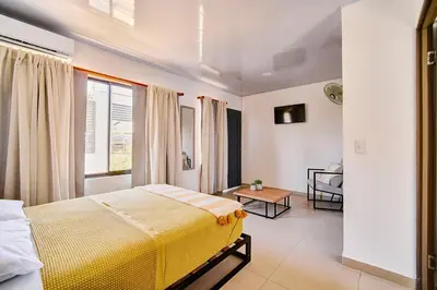 a bedroom with a yellow bed and a table at Modern Caribbean Studio - Roosevelt in Puerto Limón