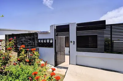 a house with a door and a garden with flowers at Modern Caribbean Studio - Roosevelt in Puerto Limón