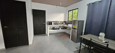 a kitchen with black doors and a table and a refrigerator at Casa Eden Near Manuel Antonio in Manuel Antonio