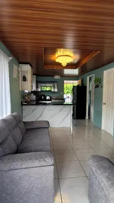 a living room with a couch and a kitchen at Marlin Vacations Home in Savegre