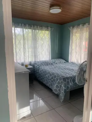 a bedroom with a bed with blue walls and windows at Marlin Vacations Home in Savegre