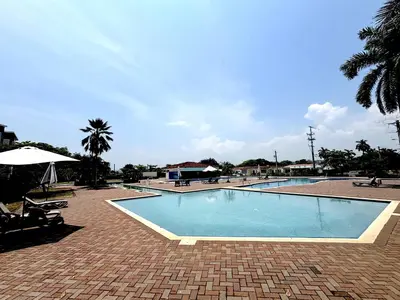 a large swimming pool in a resort with a palm tree at Beachfront Getaway, AC, Pools and Sunset Views in Bejuco