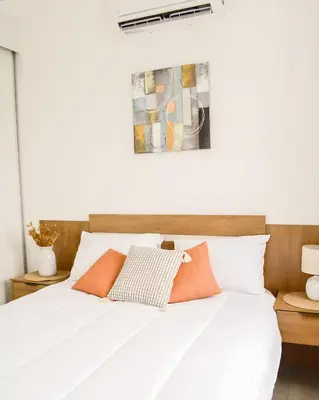 a bedroom with a white bed with orange pillows at Gaia Retreat - Núcleo Sabana in San José