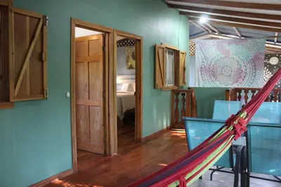 a room with a hammock and a room with a bed at Brisas del Caribe 3 in Tapantí