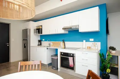 a kitchen with white cabinets and a blue wall at Catorce Urbano in San José