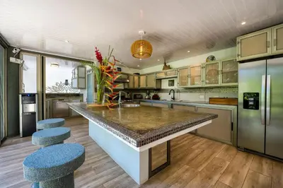 a kitchen with a large island with blue stools at Synergy Costa Rica in Uvita
