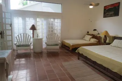 a bedroom with two beds and two chairs and a window at Apartamento Karibu in Manuel Antonio