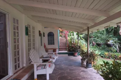 a porch with white chairs and stairs and plants at Apartamento Karibu in Manuel Antonio