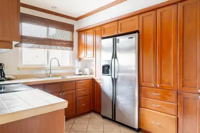 a stainless steel refrigerator in a kitchen with wooden cabinets at Casa del Mar - Veranda Retreat Pool and Balcony in Herradura