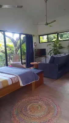 a bedroom with a bed and a couch and windows at Casa Caladium in Manuel Antonio