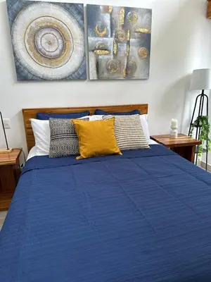 a bedroom with a blue bed with two paintings on the wall at Walk to Private Beach Luxury amidst Nature in Puntarenas