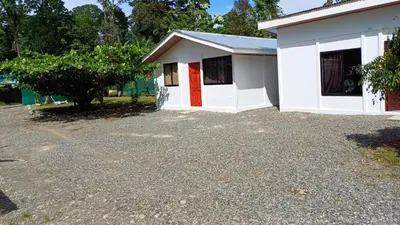 a small white building with a red door at Casitas katia in Tapantí