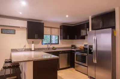 a kitchen with stainless steel appliances and black cabinets at The Cove Door 15 and 16 Upper & Lower Unit in Ocotal