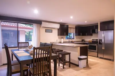 a kitchen and dining room with a table and a counter top at The Cove Door 15 Main Floor Unit in Ocotal