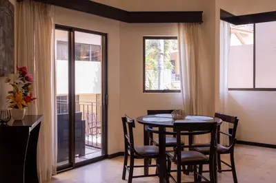 a dining room with a table and chairs and windows at The Cove Door 16 2 Bedroom Upper Unit in Ocotal