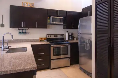 a kitchen with black cabinets and stainless steel appliances at The Cove Door 16 2 Bedroom Upper Unit in Ocotal