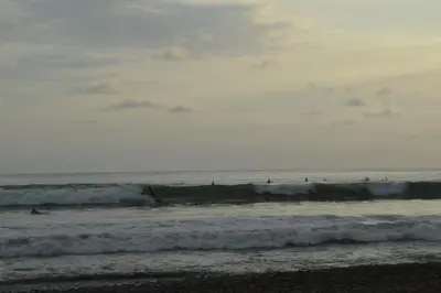 a group of people riding the waves in the ocean at Hostel Piramys in Tapantí