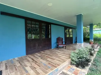 a porch of a house with a wooden door and a chair at Nature, Peace & Tranquility in Northern Costa Rica in Santa Rita