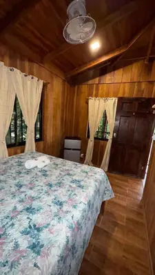 a bedroom with a bed in a room with wooden walls at Cabaña Nacahome in Santa Cruz