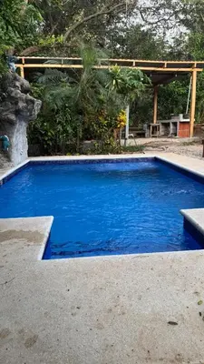 a swimming pool with blue water in a yard at Cabaña Nosara in Santa Cruz