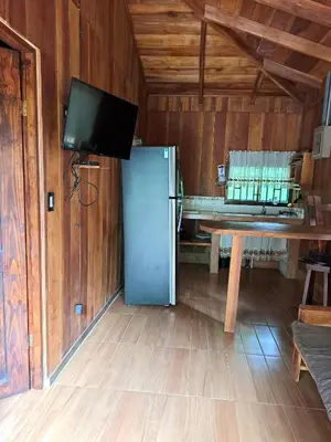 a room with a refrigerator and a table and a tv at Cabaña Nayuribe in Santa Cruz
