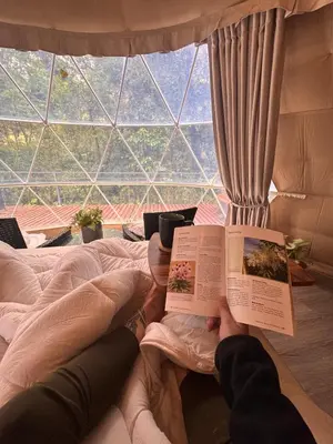 a person laying on a bed reading a book at Epífita, Bosque Nuboso Glamping Monteverde in Monteverde Costa Rica