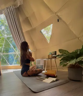 a girl sitting on the floor in a room with a window at Epífita, Bosque Nuboso Glamping Monteverde in Monteverde Costa Rica