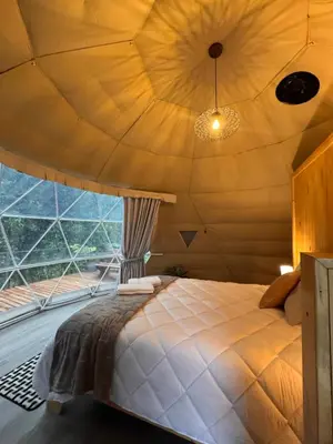 a bed in a room with a large window at Epífita, Bosque Nuboso Glamping Monteverde in Monteverde Costa Rica