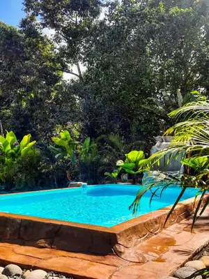 a swimming pool in a garden with trees at Iki Room with Jacuzzy in Fortuna