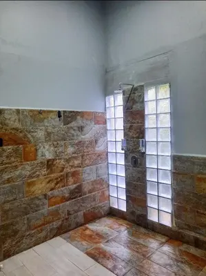 a bathroom with a shower with a stone wall at Iki Room with Jacuzzy in Fortuna