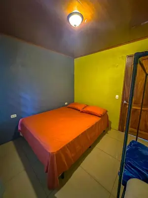 a bedroom with a bed with an orange blanket at Costa Amanecer in Uvita