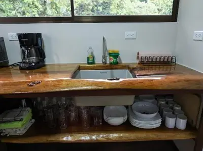 a kitchen counter top with a sink and plates at VILLA SANTA LUCÍA in front of the waterfall with a mountain view in Ceibo